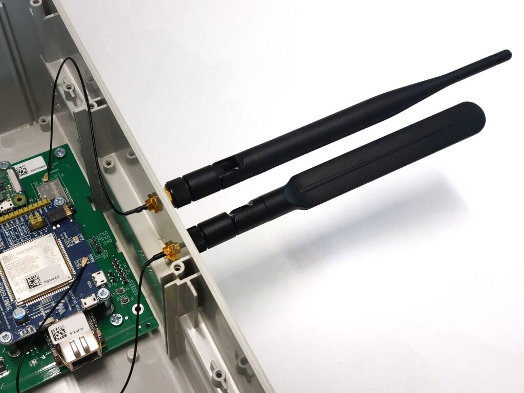 A close-up of the same side panel of the enclosure, but with the two black antennas already screwed in. A photo showing the "after" state following the correct installation of the antennas on one side.