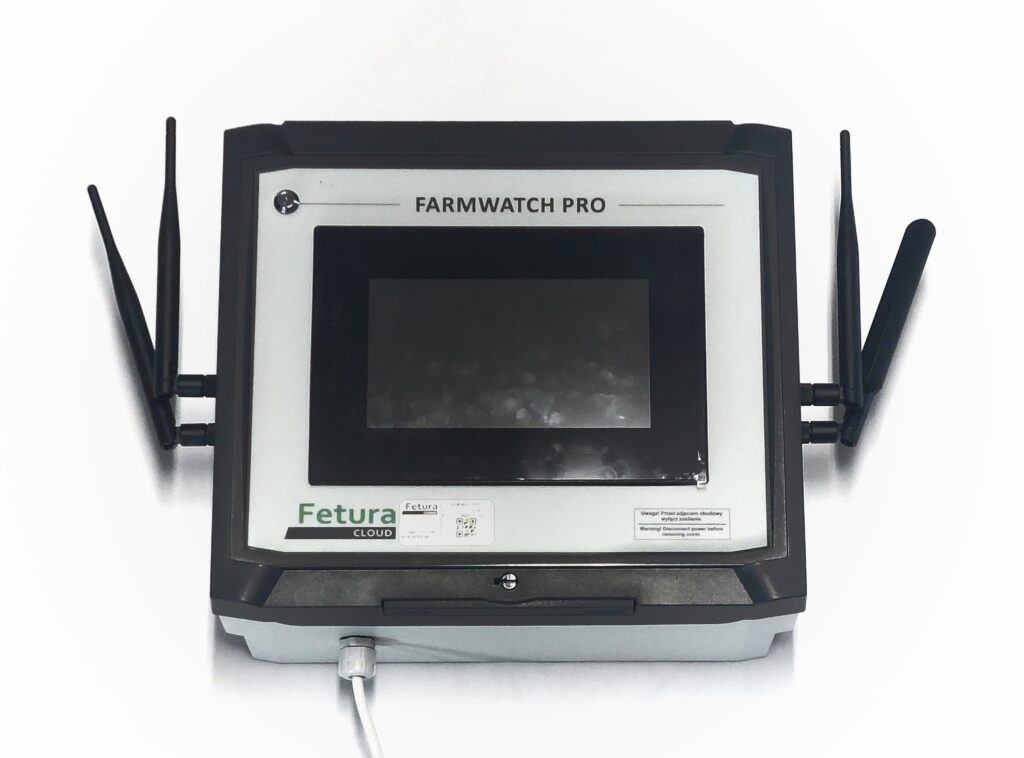 The photo shows a fully assembled, enclosed FARMWATCH PRO unit. Four black antennas, secured with screws, are visible on the outer sides of the enclosure. The front features a screen and a sticker warning that the power must be disconnected before removing the housing. Ideal as the main photo (showing the final result).