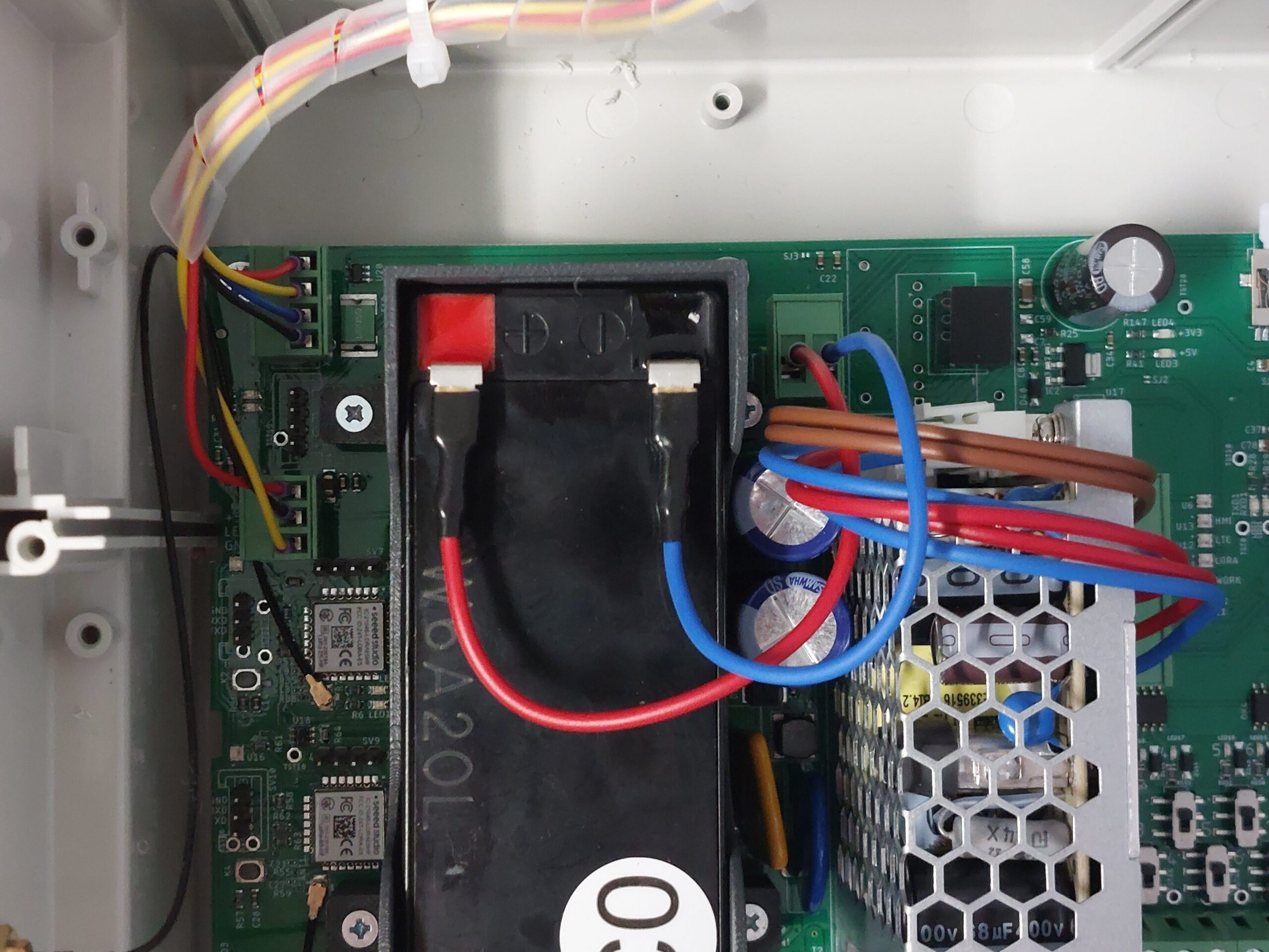 A close-up of the battery showing the wiring correctly and securely connected (the "after" state). The red wire is connected to the positive (+) terminal, and the blue wire is connected to the negative (-) terminal.