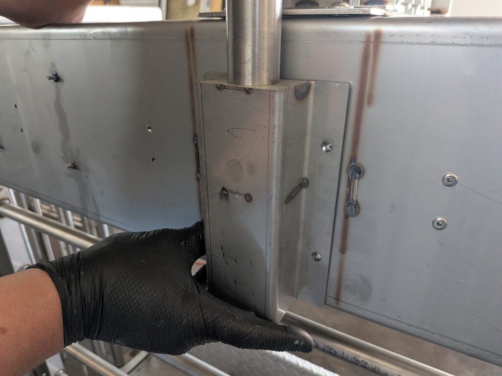Technik przykłada aluminiowy słupek montażowy do ściany klatki separacyjnej, przygotowując go do przykręcenia śrubami imbusowymi.