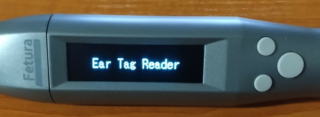 Obraz przedstawia ekran skanera 2 i 3 ze zbliżeniem na ekran i przyciski. Na ekranie widnieje napis przy uruchamianiu urządzenia "Ear Tag Reader".